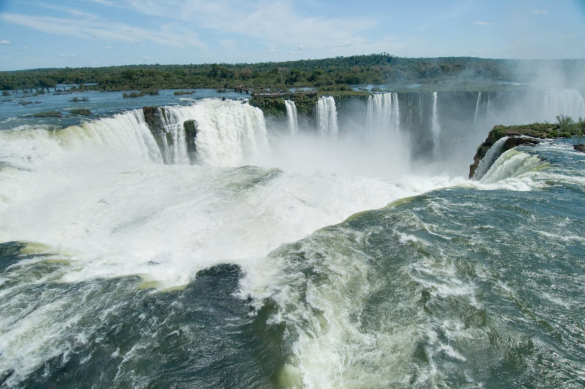 Rio Iguaçu em grande volume na Garganta do Diabo, com as quedas ao fundo e a mata ao redor
